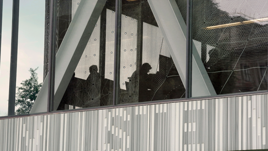 From the outside, looking into an office space, you can see the silhouettes of people sitting.
