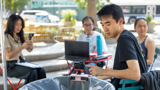 Trashcan fitted with a camera being examined by students