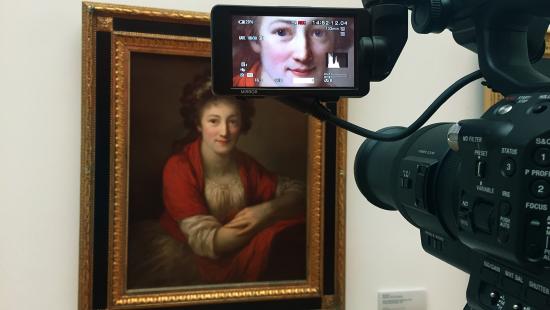 A camera pointed at a painting with a close up shot appearing in the viewfinder screen.
