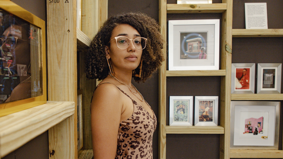 woman wearing glasses and a leopard print dress leaning against a roughly framed wall