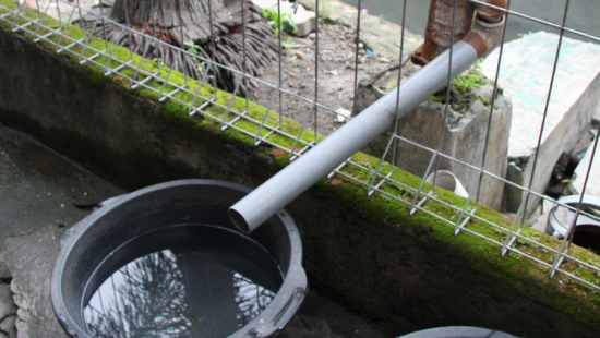 A hand pump used for extracting water next to a bucket.
