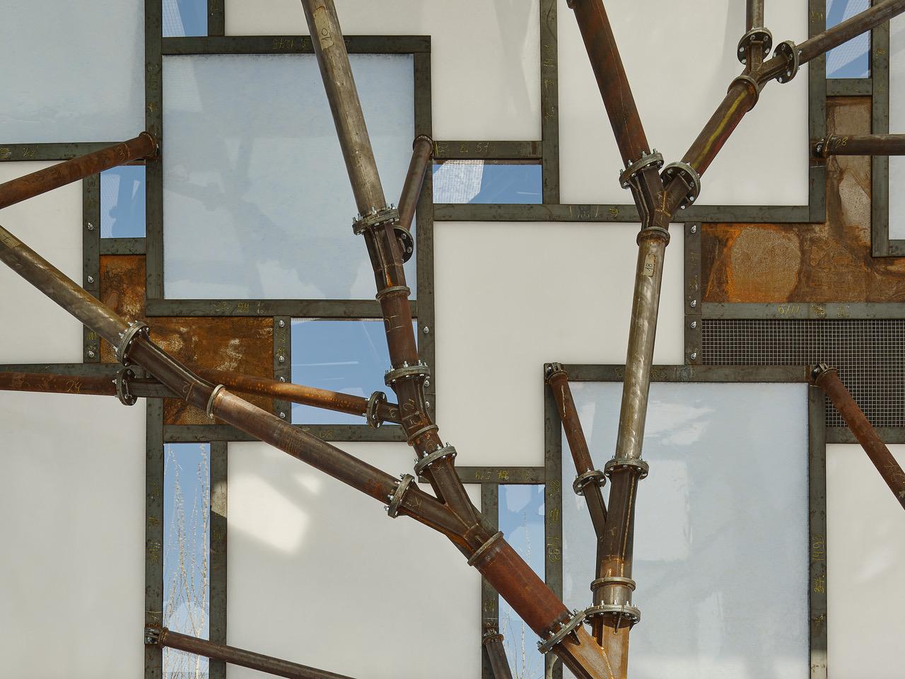 blue, white, and brown stained glass behind metal branch construction