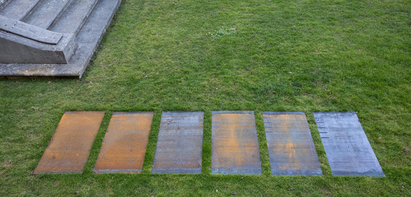 Image of 6 iron plates embedded in turf of a well kept garden