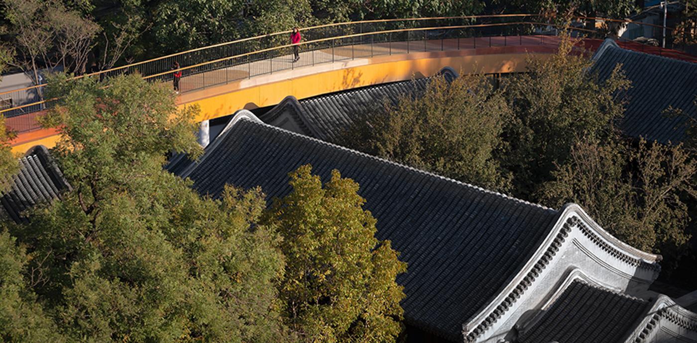 A colorful yellow walkway elevated above a historic 18th-century Siheyuan courtyard