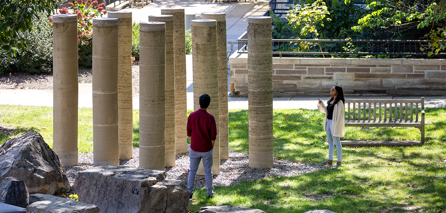 People observing large stone pillars coming out of the ground.