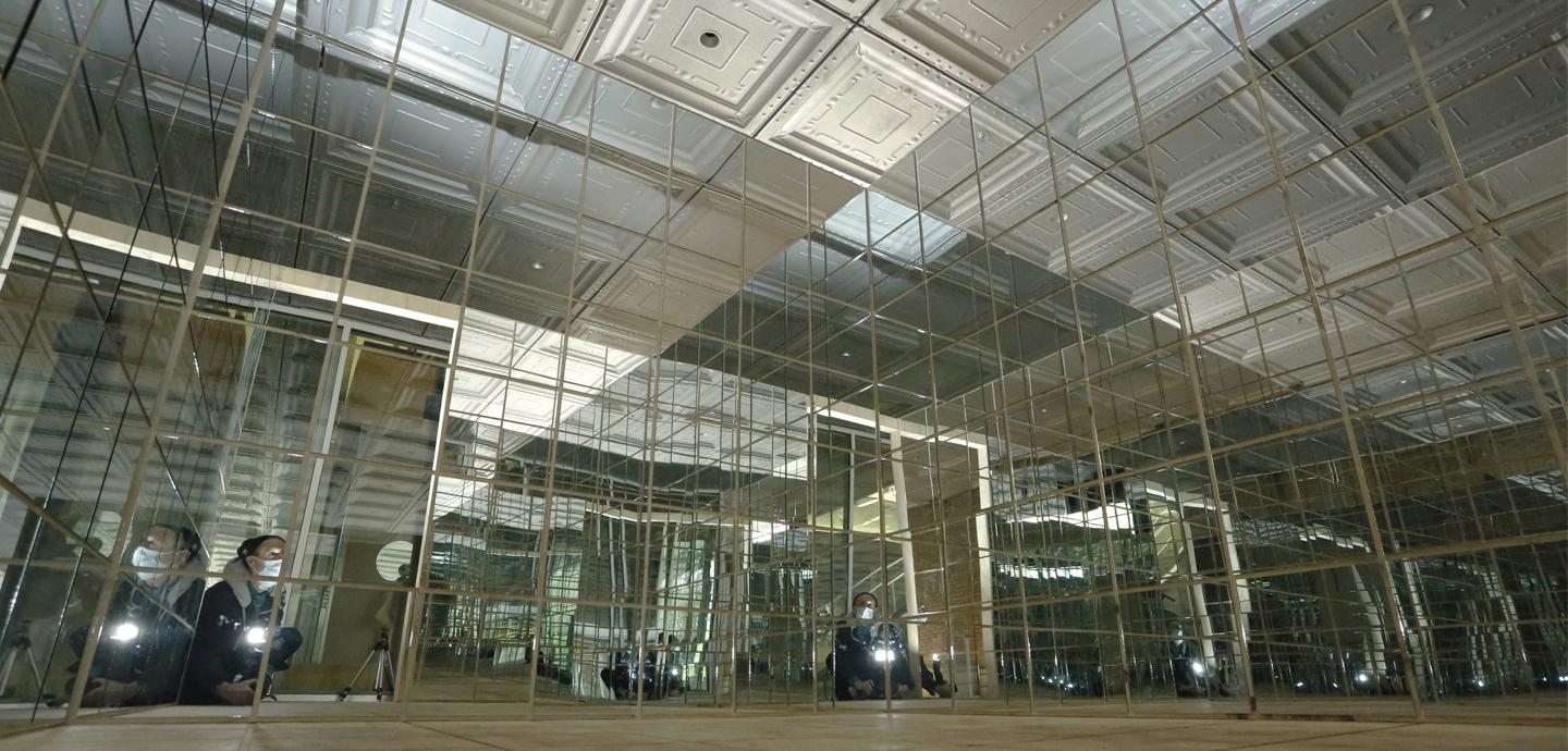 A view of a cube structure from within covered in mirrors.