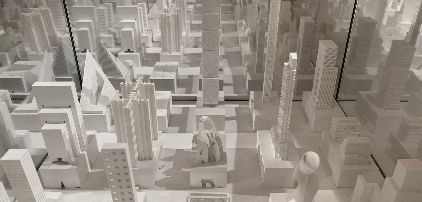 White models of buildings sit on a white base with three mirrored sides.