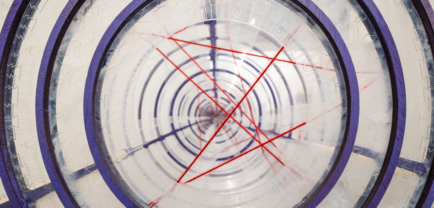 Side view of a row of purple concentric circles arranged in a tunnel, with red thread connecting them.