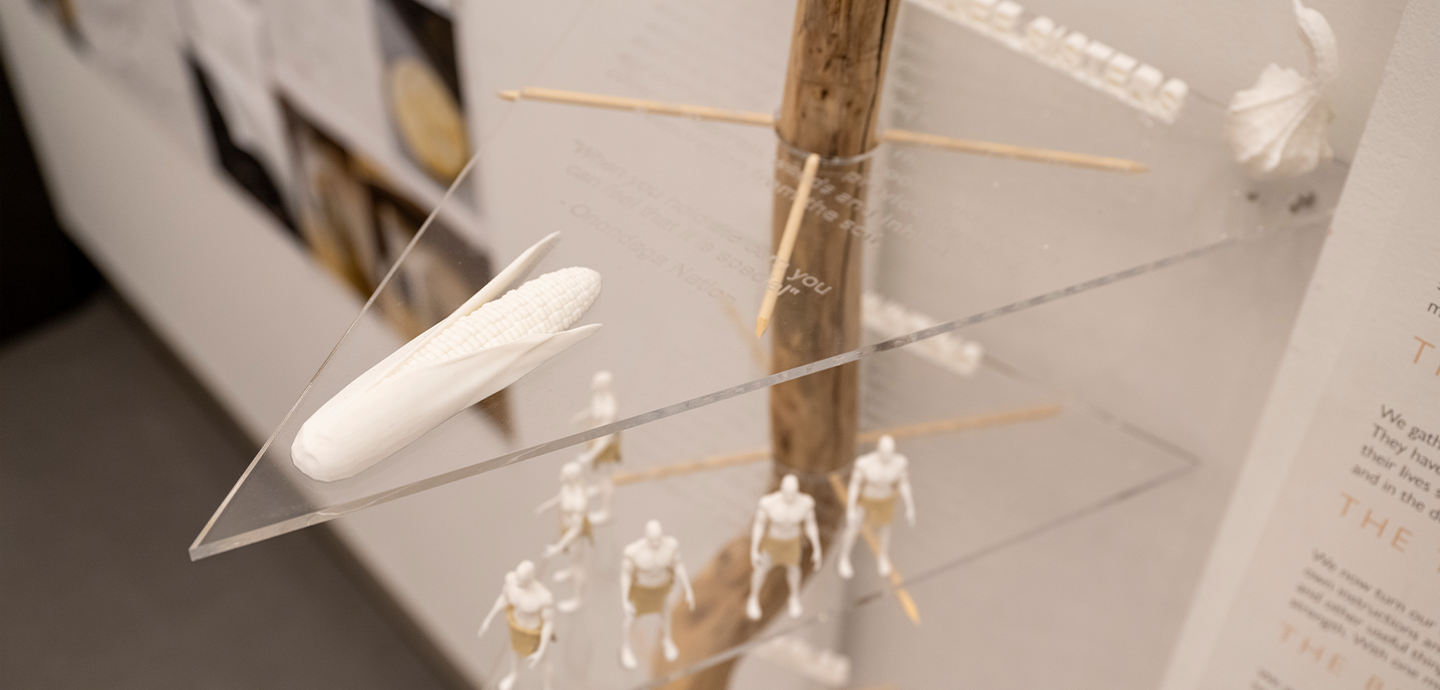 A vertically mounted branch supports acrylic triangles positioned as platforms, with models of people on the middle platform.