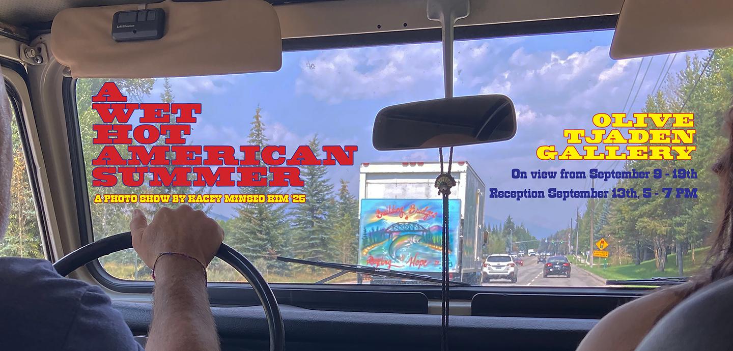 A view of a highway out the windshield of a car, with trees lining the road and a blue sky above. The information about the exhibition is written on top in colorful red and yellow lettering.