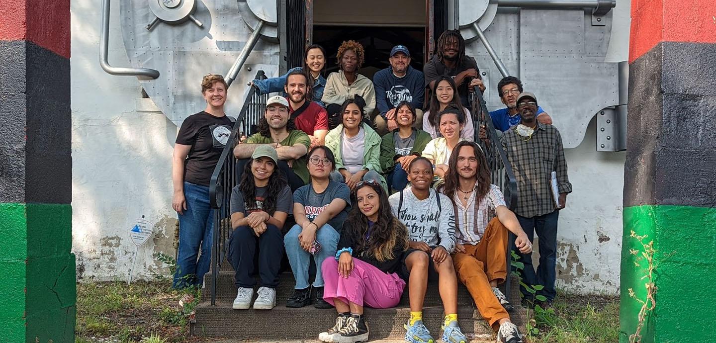 A large group of people sitting on a set of porch stairs smilling at the camera.