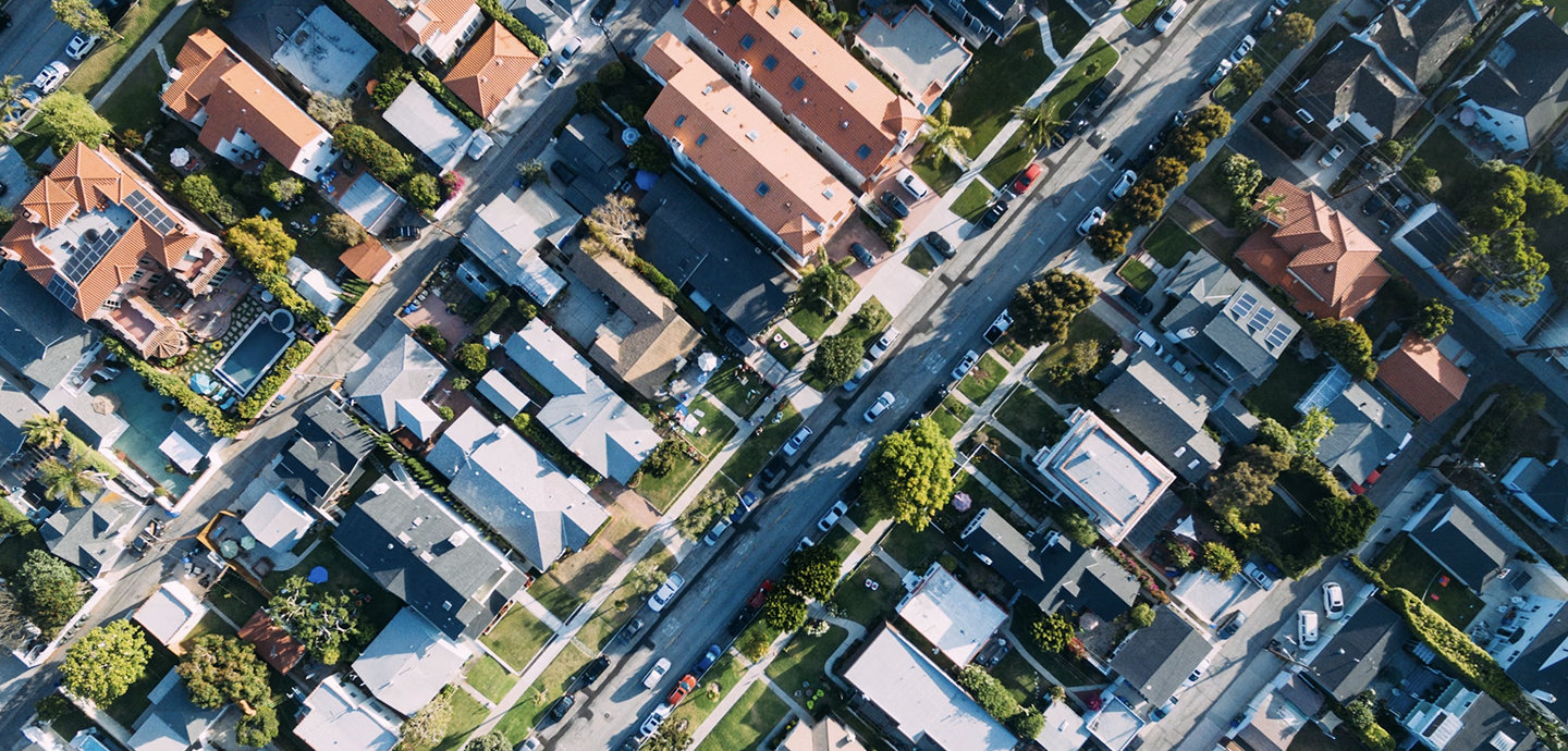 aerial view of neighborhood with houses, streets, trees, and cars