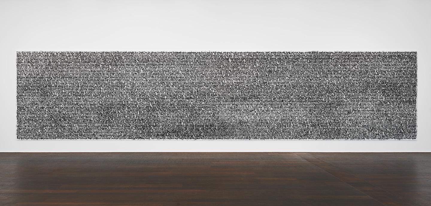A photo of a white wall with a large, rectangular black painting on it. The painting looks like a long string of text, but the photo is taken from too far away to read any of the words.