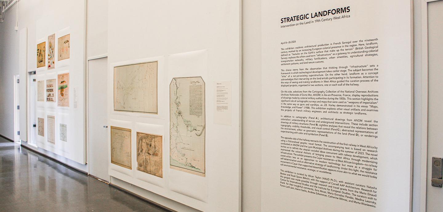 Exhibition hallway with drawings and text description hung on wall.