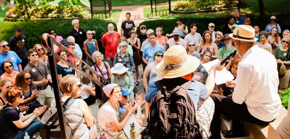 A group of people gathering around and listening to a speaker.