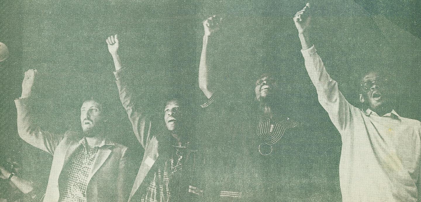 A newspaper print of four people standing with their fists held up.