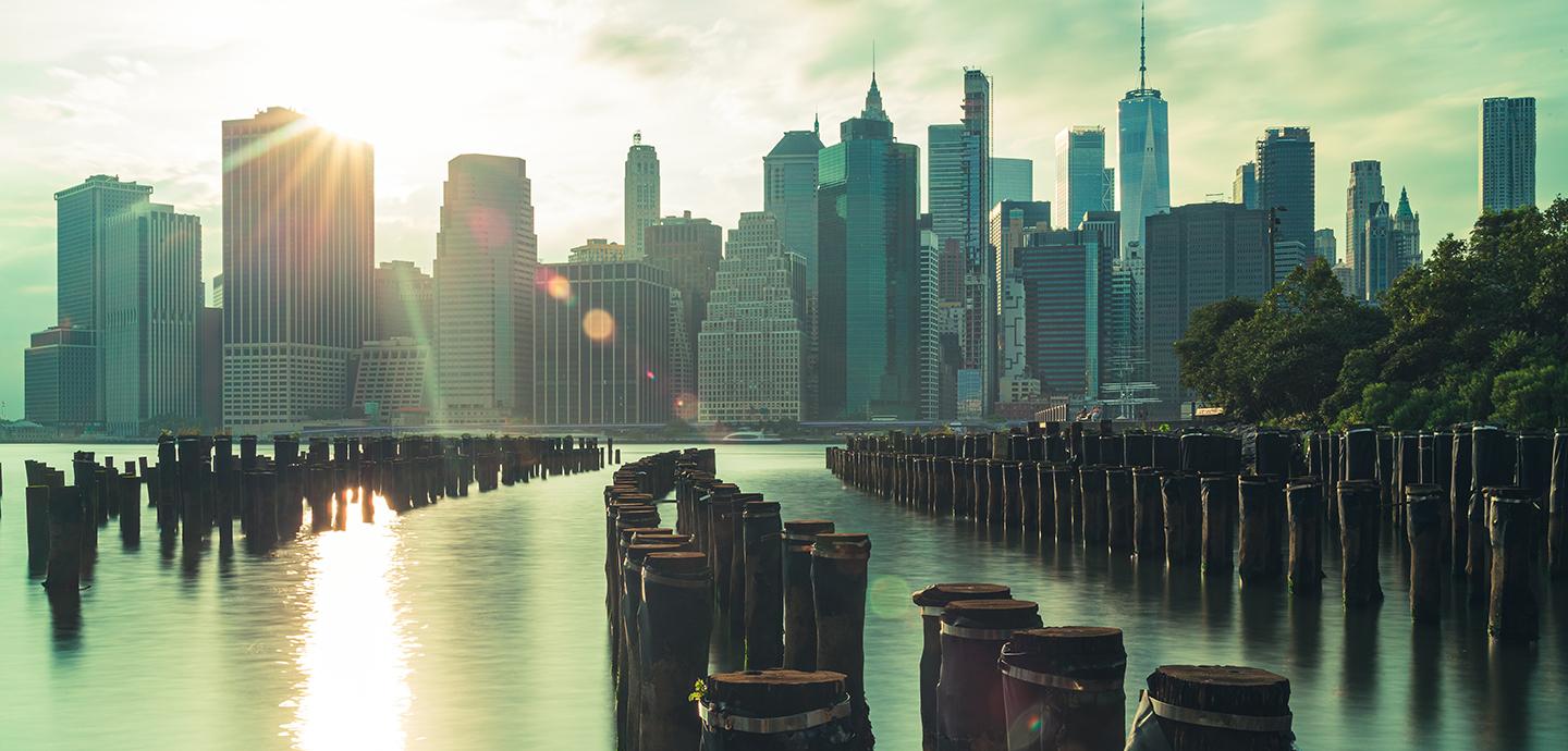 NYC skyline with a waterfront view and sun shining