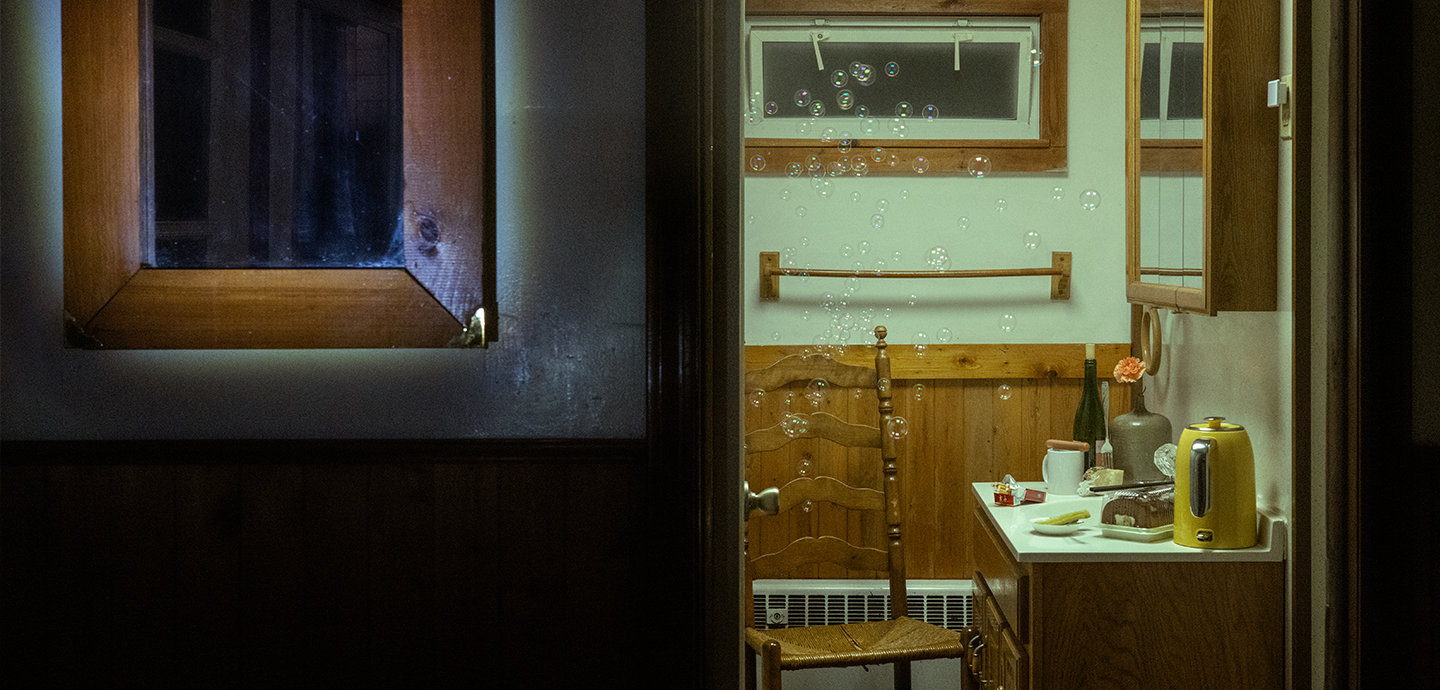 Peering into a room with a chair and an end table with desserts and a kettle.