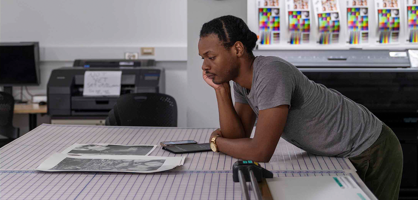 Person leaning over a grid patterned table examining photographs.