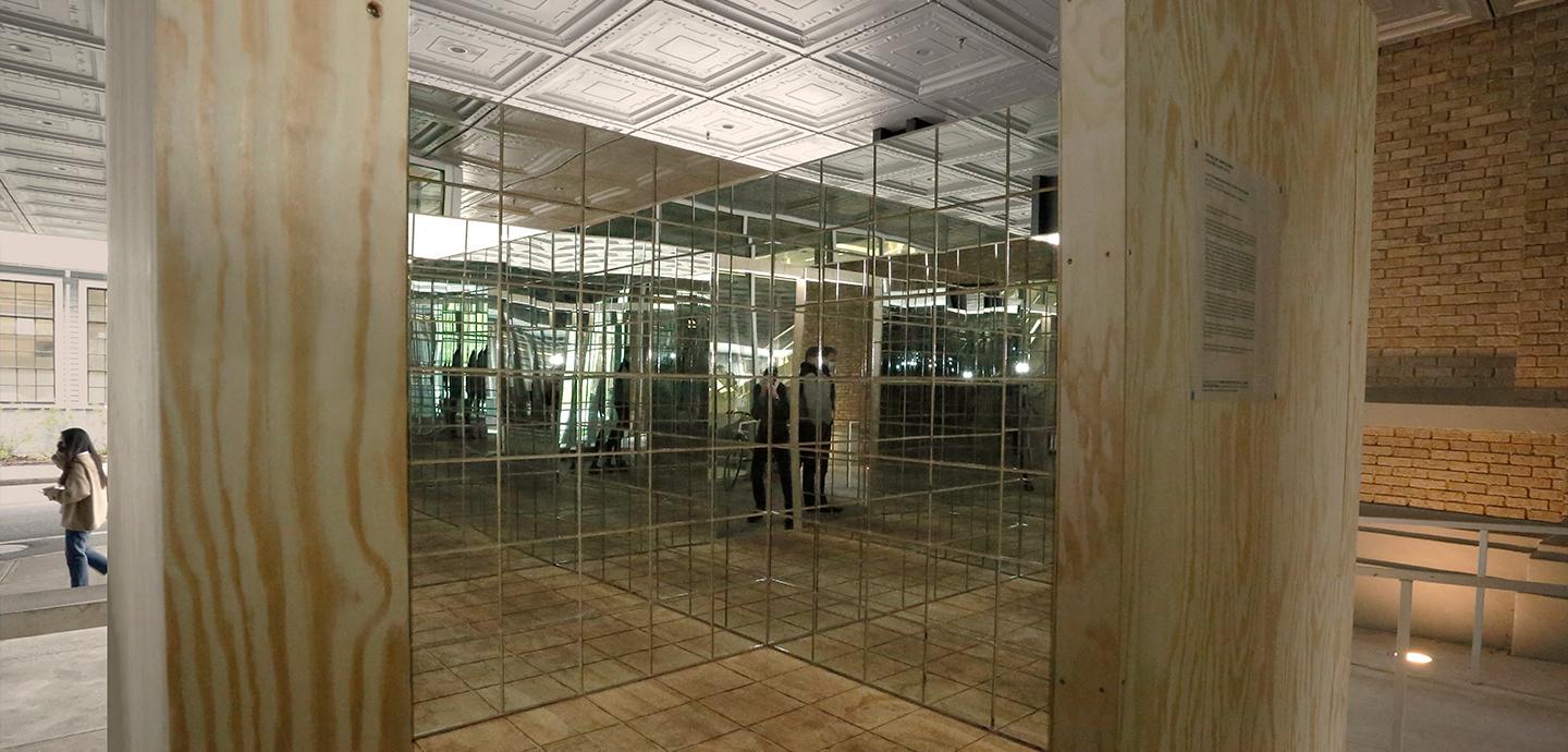 A ply wood box with a doorway showing walls of mirrors within.