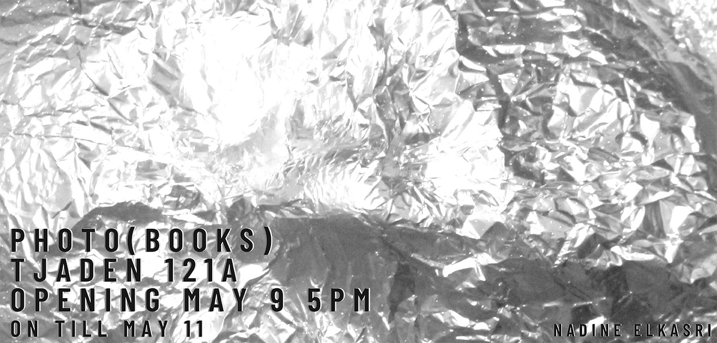 Aluminum foil or mylar with black text over it reading PHOTO (BOOKS) TJADEN 121A  OPENING MAY 9 5PM ON TILL MAY 11. 
