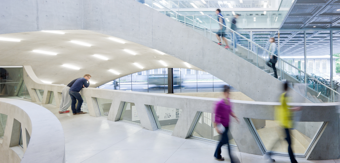 People walking within a glass, metal and, concrete building