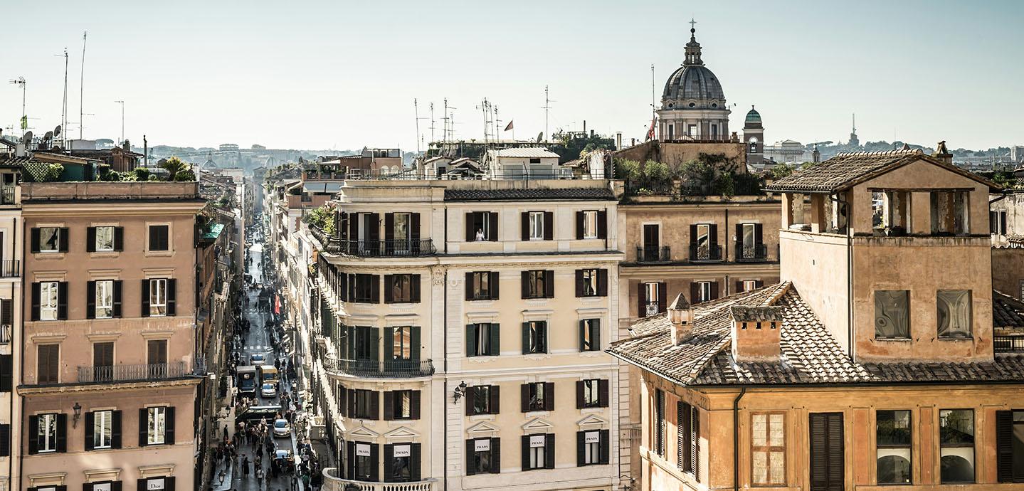 View from the upper story of a building looking down a busy street in Rome