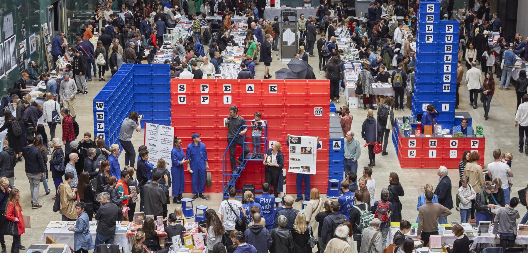 Image of a crowded large room with red and blue stands