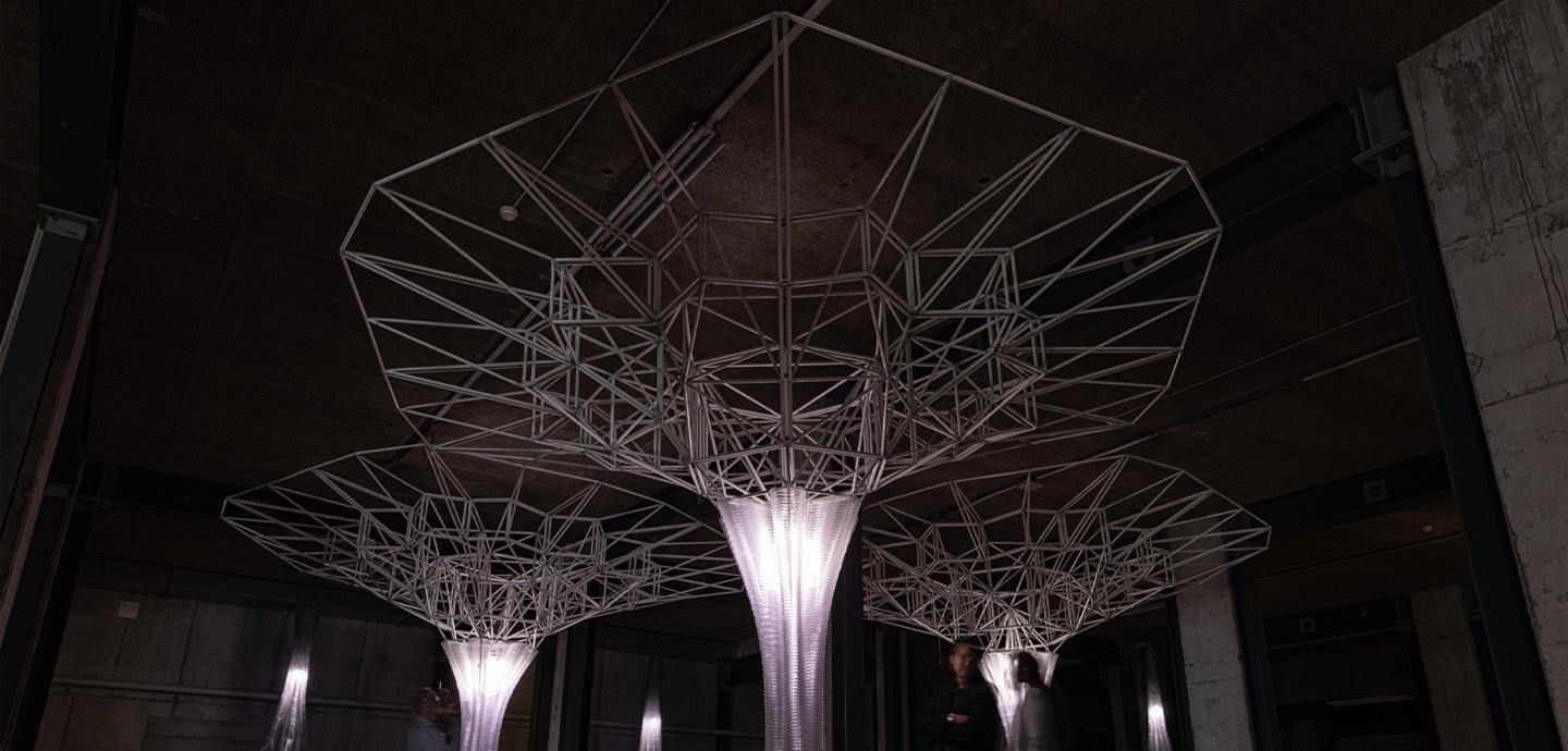 Three illuminated columns topped with intricate lattice structures.