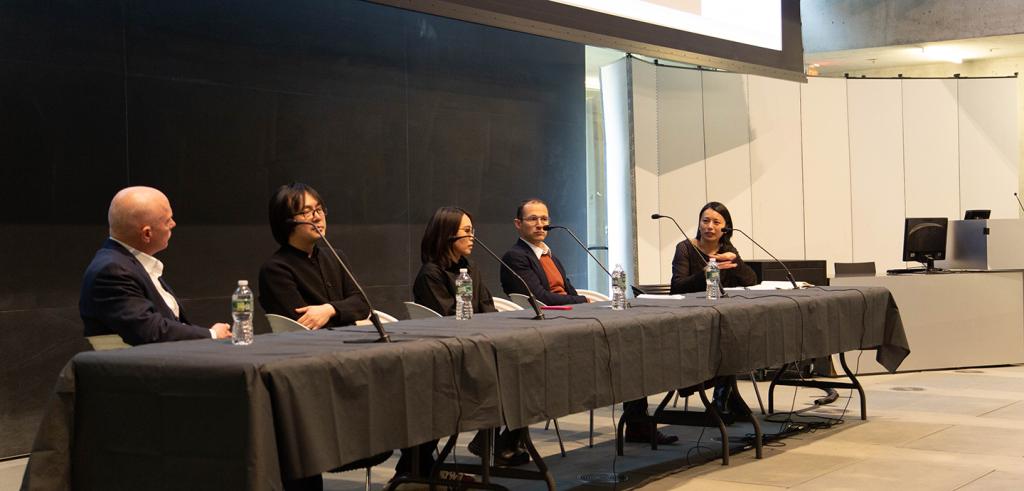 Panelists sitting a table with microphones.