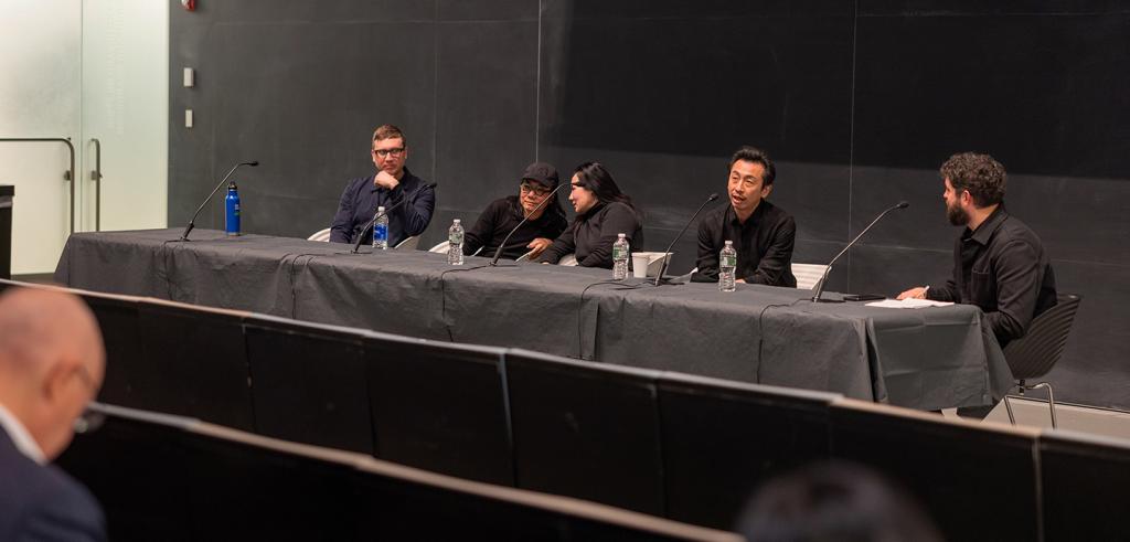 Panelists sitting a table with microphones.