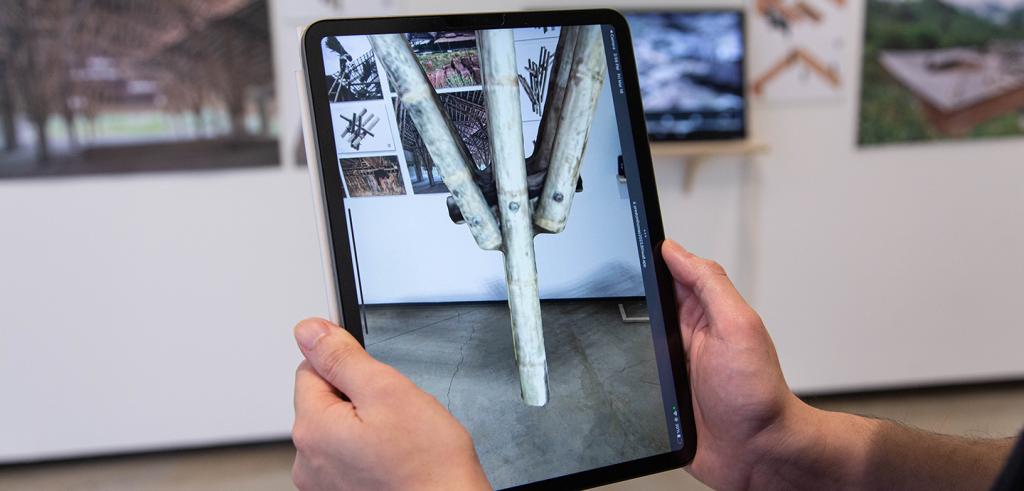 A person holding a electronic tablet device with augmented reality images shown on the screen.