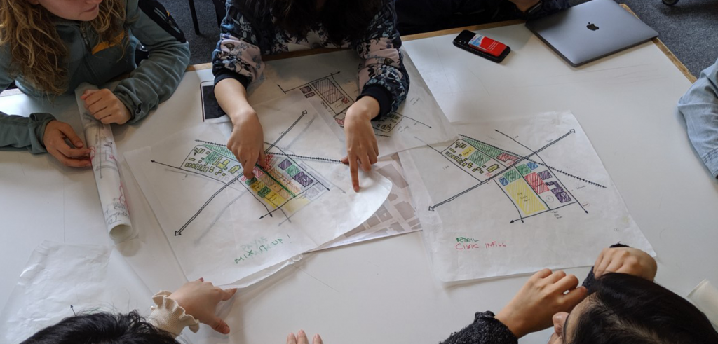 table surrounded by people with hands on hand sketches