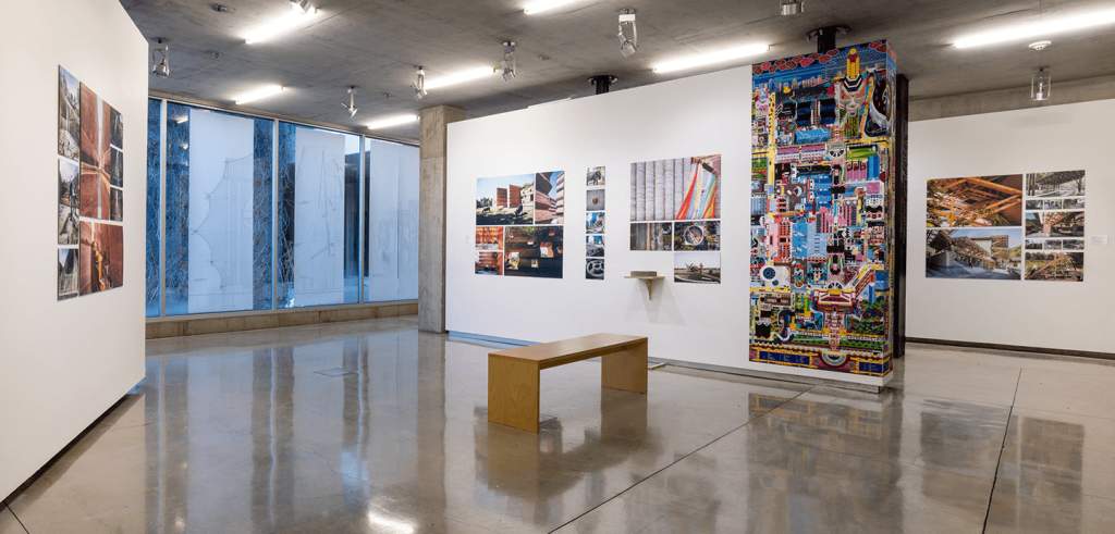 An empty gallery with artwork on the wall and a single bench.