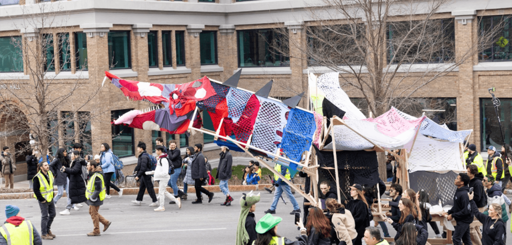 People parading with a large handmade dragon sculpture.