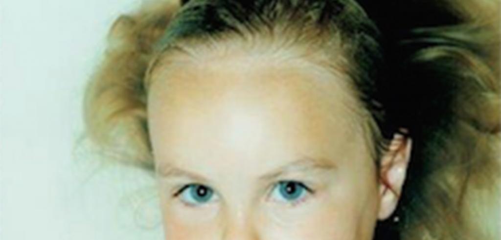 Young blonde girl with blue eyes staring at the camera.