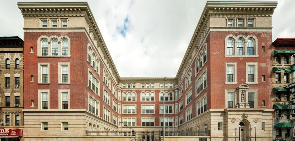 Large brick building, 5 stories high with concrete molding NYC with a street view. 