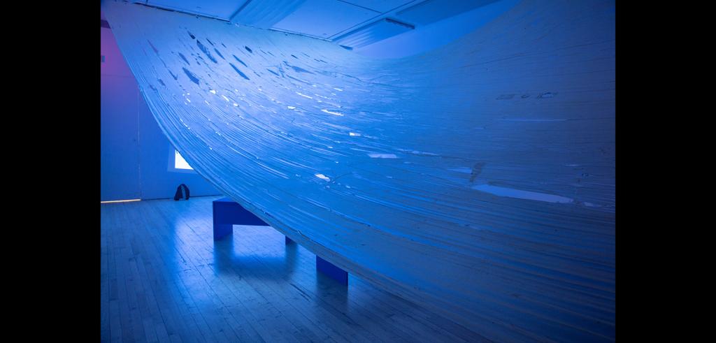 Dark room with a blue hue with a large piece of holy fabric draped across the ceiling.