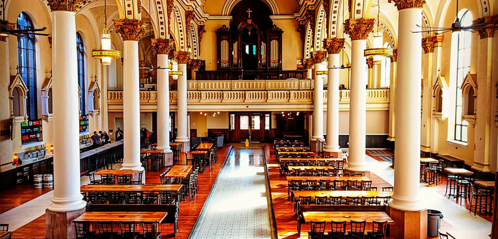 A church building with large white pillars and tables with chairs throughout.