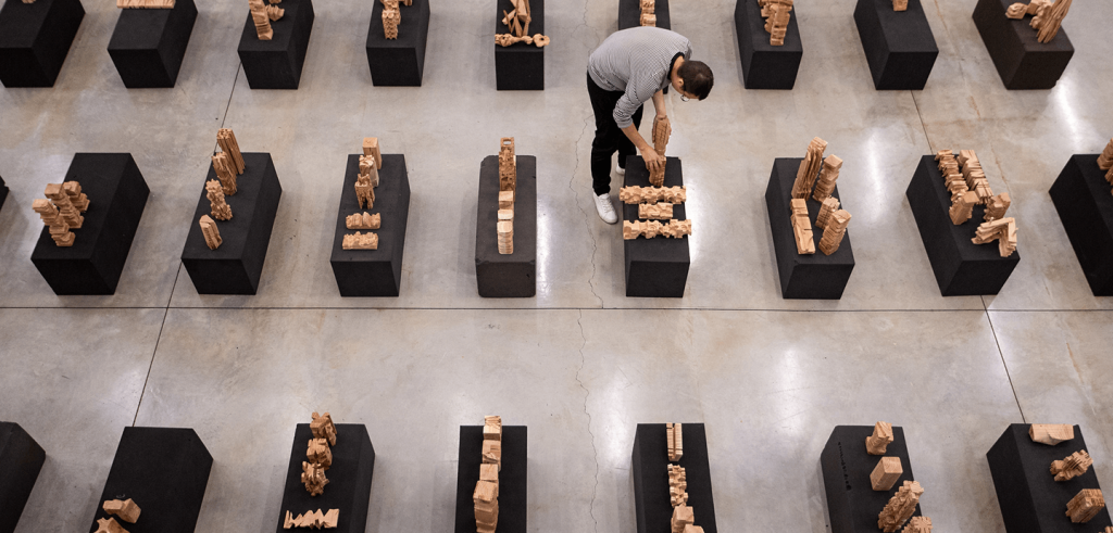 A person setting up wooden models on black pedestals.