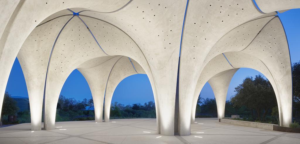 A concrete pavilion whose top extends upwards to create an irregular triangular grid roof. 
