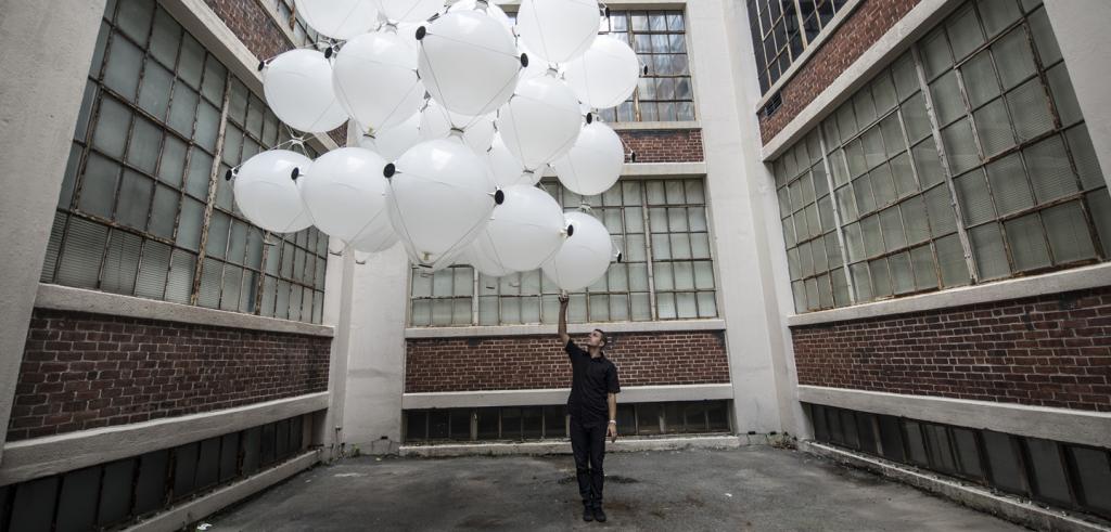 inflated white objects being held by a person in a courtyard of a brick building