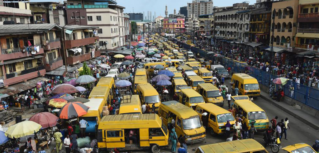 Busy street filled with yellow vehicles, umbrellas, people and buildings.