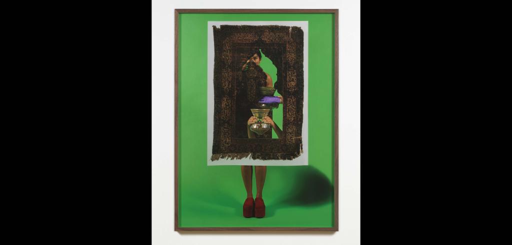 Person wearing red platform shoes against a green background in a wooden frame behind a cut out old carpet holding a vase.