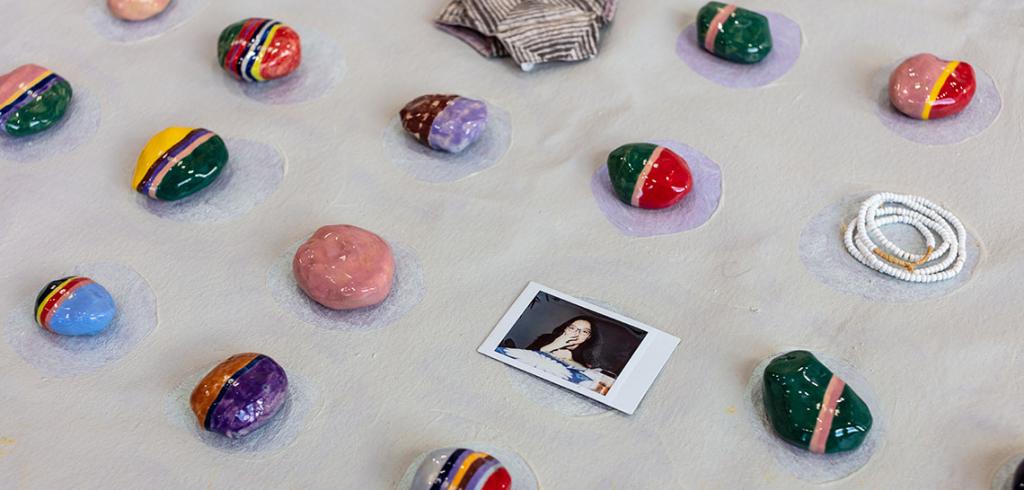 Various painted rocks in bright colors laid out in a grid pattern.