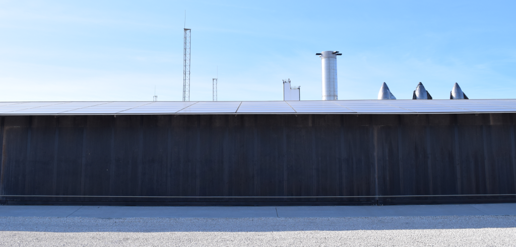 A large sheet metal structure with a bright blue sky.