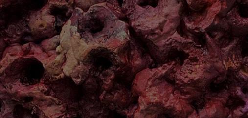 Reddish brown colored piece of ground with craters formed in it.