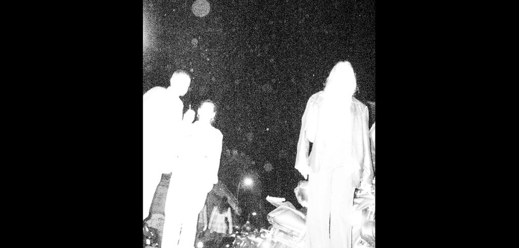 three people with bright white silhouettes with a black night sky behind them.