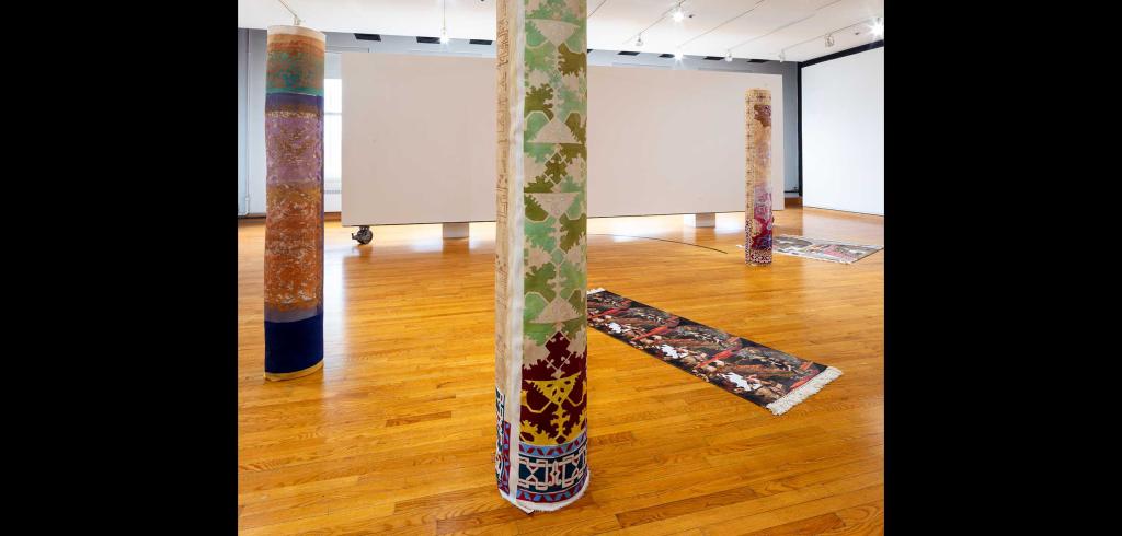 Rolled up tapestries with three standing up and two laying on the ground.