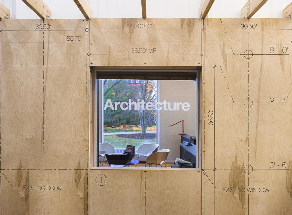A window with the word ARCHITECTURE surrounded by wood paneling with various dimensions around it